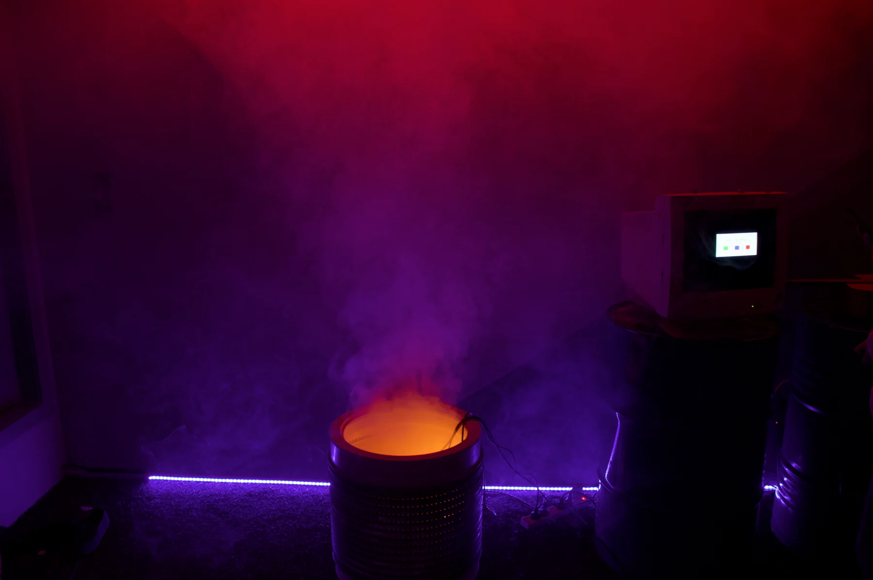 A steaming pot in a room lit purple and pink.