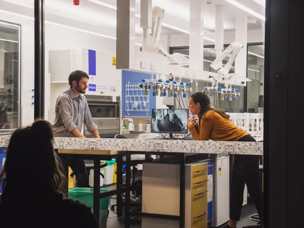 Two performers across a laboratory bench in RUR 2020.