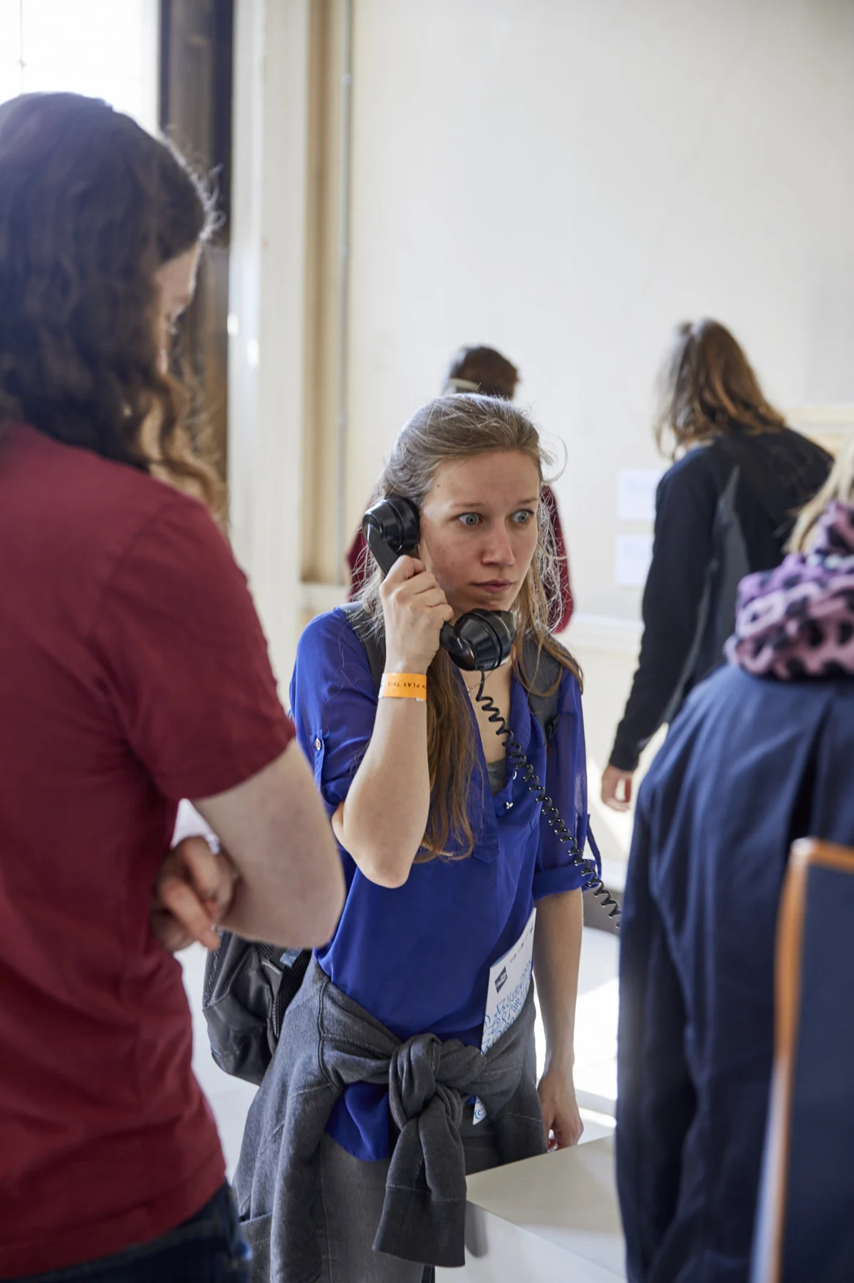 A visitor at the telephone plinth, with others watching.